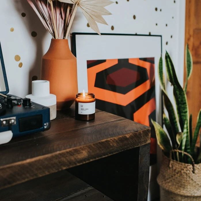 Handmade Candle Co. Amber & Musk Soy Wax Candle sat on table next to a house plant and record player